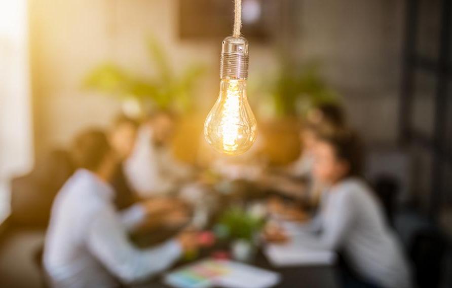 lightbulb in front of out of focus group of people at table