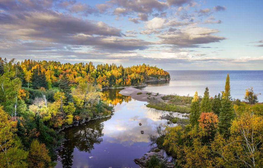 Beautiful reflections of clouds and Autumn colors on the Baptism River where it meets Lake Superior at Tettegouche State Park, Minnesota